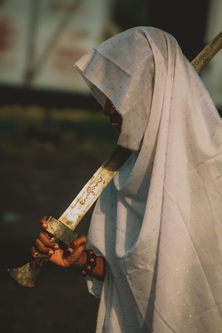 A person in traditional attire holds a sword, blending cultural heritage and craftsmanship.